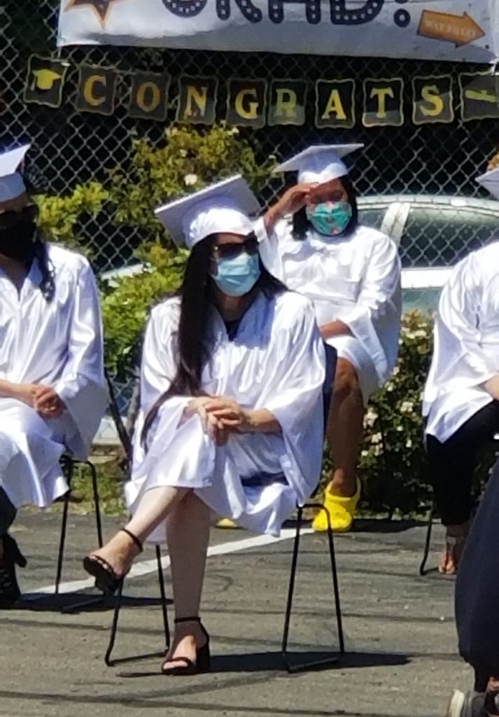 graduates sitting in caps, gowns, and masks
